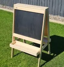 Pine double-sided chalkboard easel with a front tray, standing on a lawn