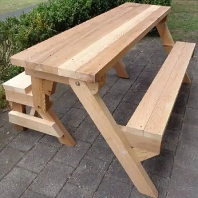 Pine picnic table with hinged bench seats on angled legs, set on a paved patio