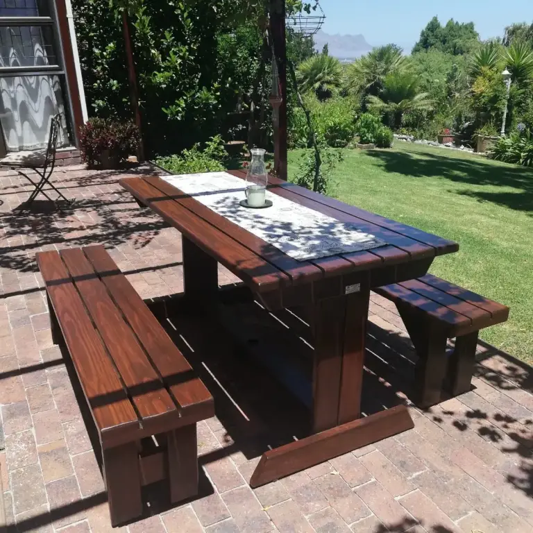 Dark mahogany-stained outdoor table with two chunky benches on a brick patio with mountain views