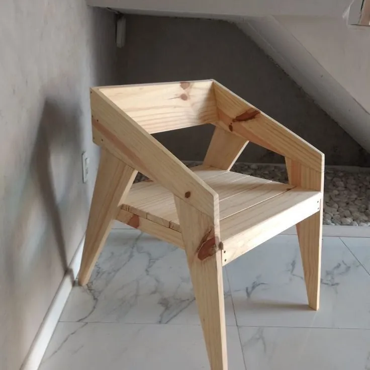 Modern pine armchair with angled splayed legs and a box-frame back on a marble floor