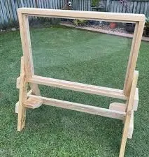 Pine frame easel with a clear perspex panel and sturdy splayed feet on a lawn