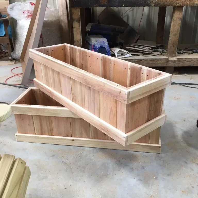 Two rectangular planter boxes with vertical boards and framed rims in a workshop