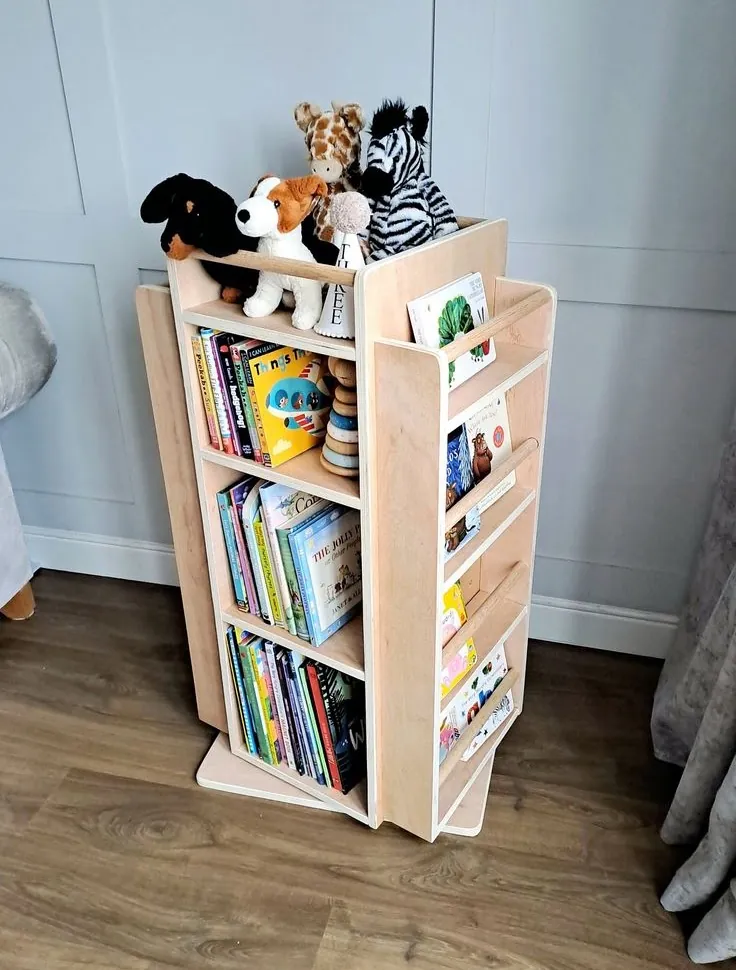 Birch plywood rotating kids' bookcase with front-facing book ledges and soft toys on top
