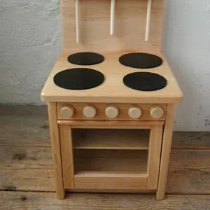 Small natural pine play stove with four black hobs, wooden knobs and an open oven compartment