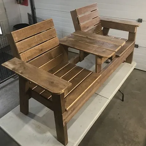 Brown stained double garden chair with wide armrests and a slatted centre table