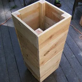 Tall tapered cedar planter box with mitred top trim on a timber deck