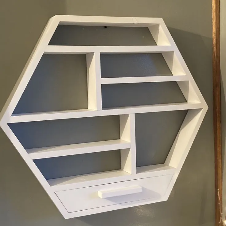 White hexagon wall shelf with compartments and a small drawer